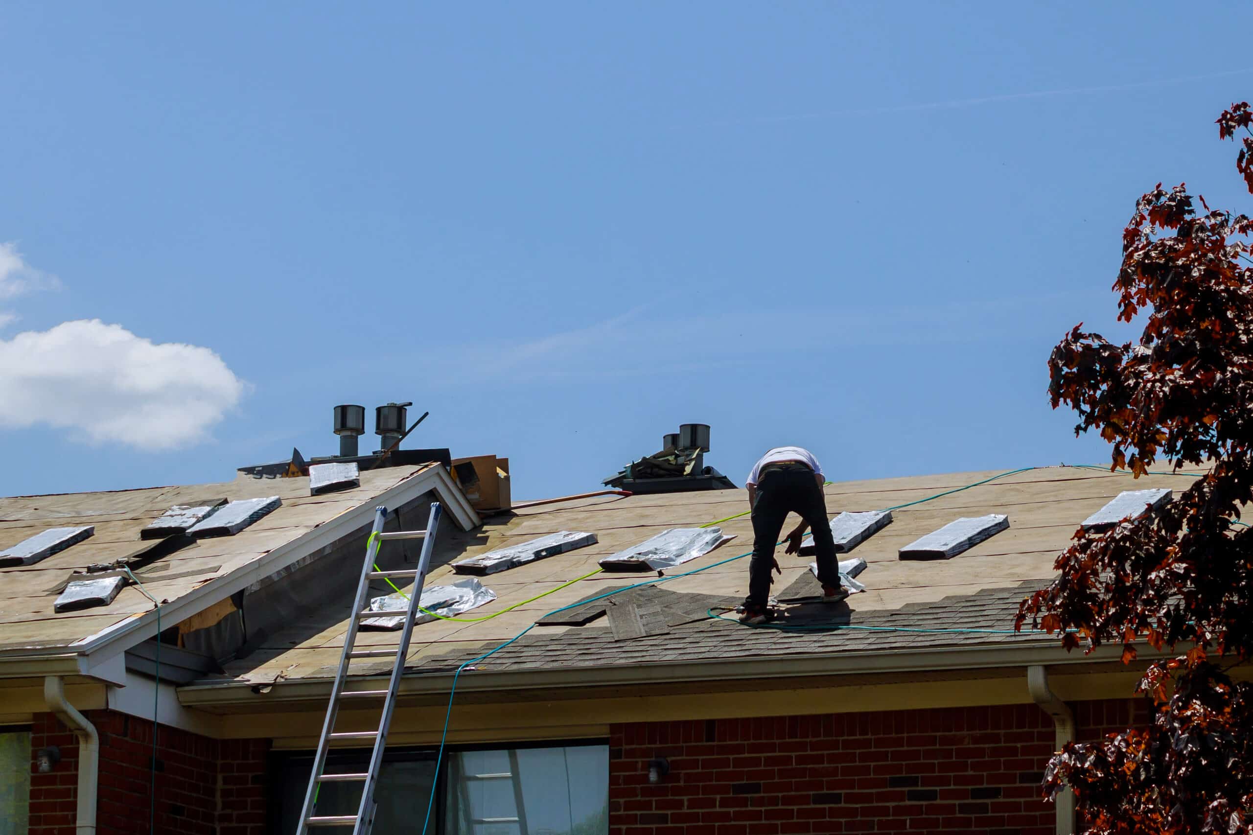 Roof repair, worker with replacing gray tiles shingles on house